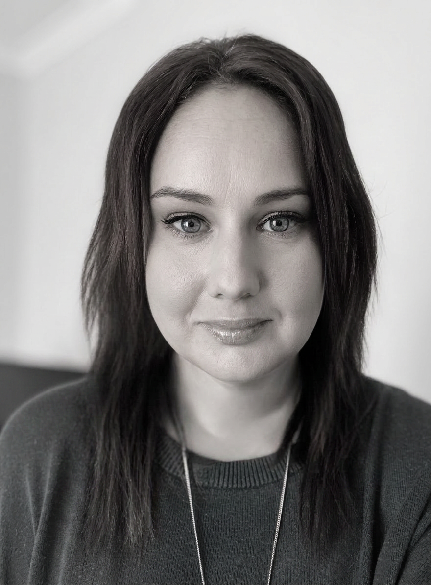 Black and white portrait of a woman with long dark hair, wearing a sweater, looking directly at the camera.